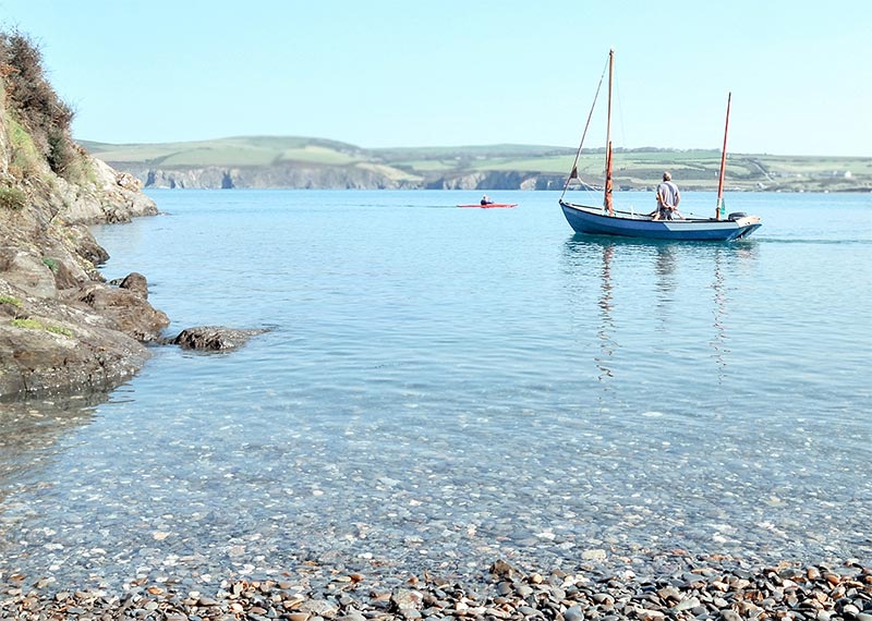 A boat leaves Cwm as a kayaker comes back to shore